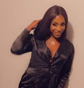 black transgender woman touches her hair and smiles at the camera